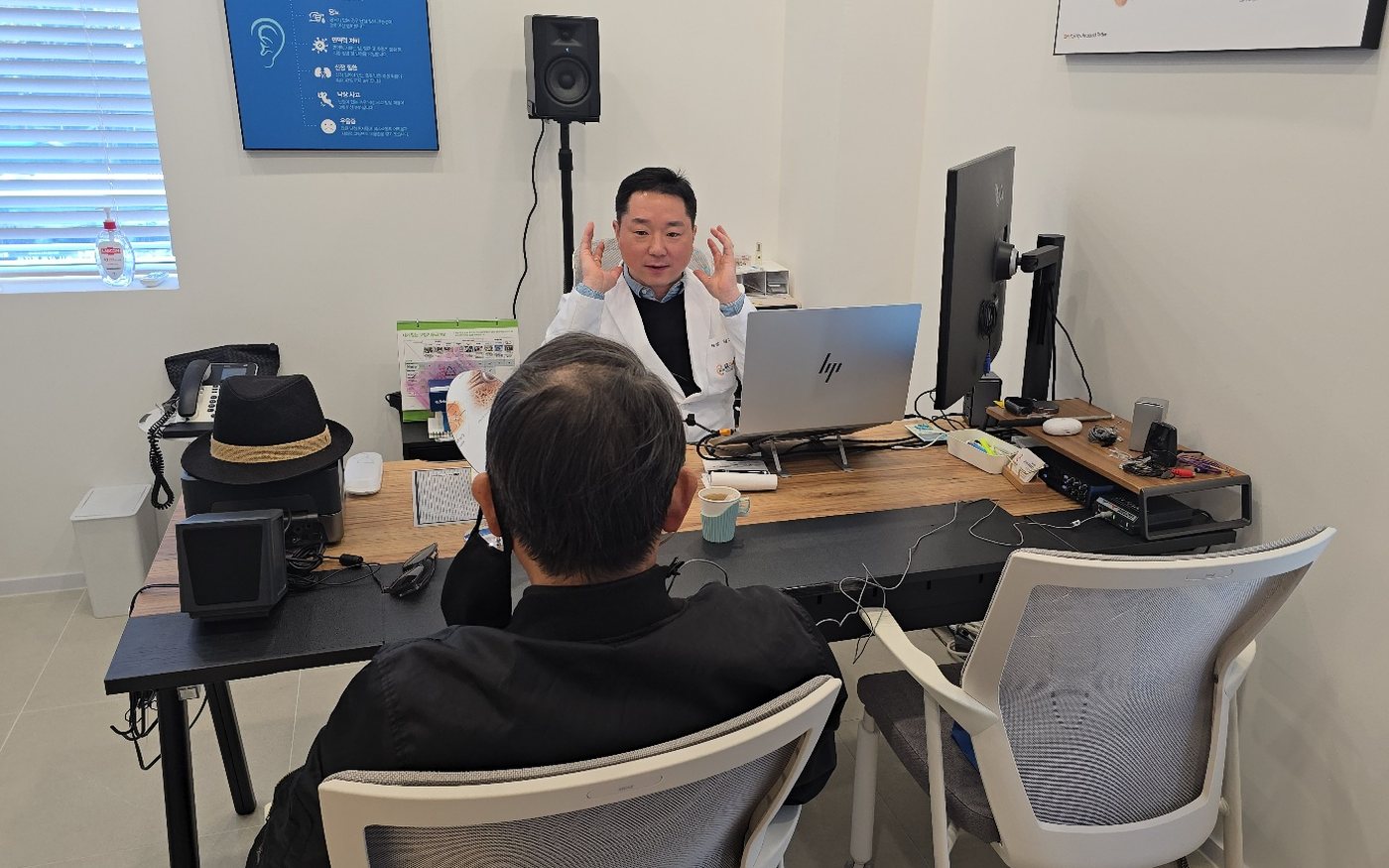 김지훈 원장이 상담 책상에서 손짓을 하며 고객에게 설명하는 모습